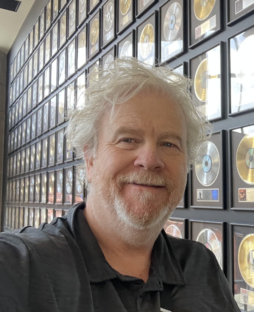 Andrew Clarke in front of a wall of gold and platinum records